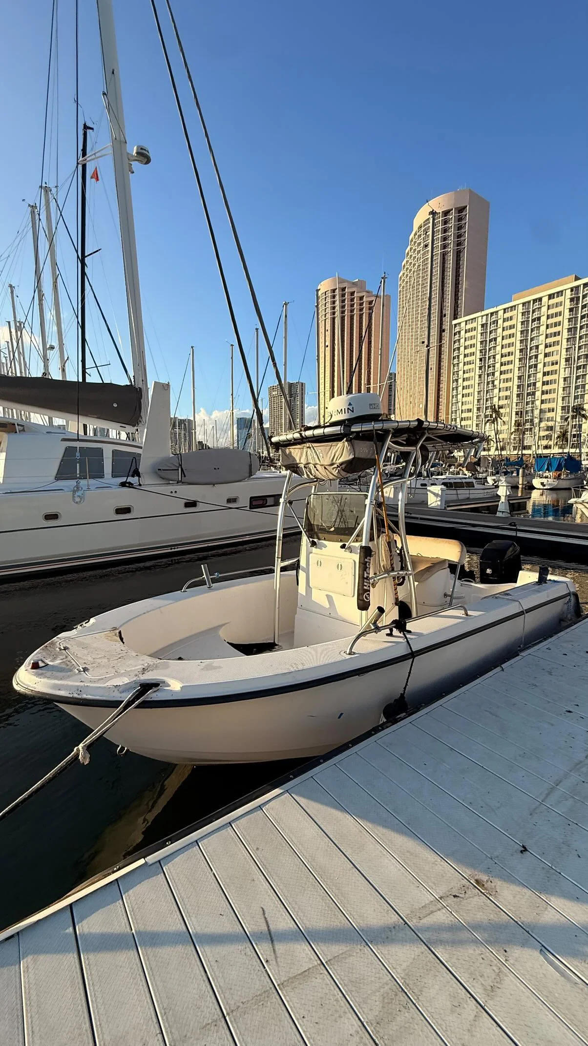 Center console boat docked at a Honolulu marina with the city skyline in the background