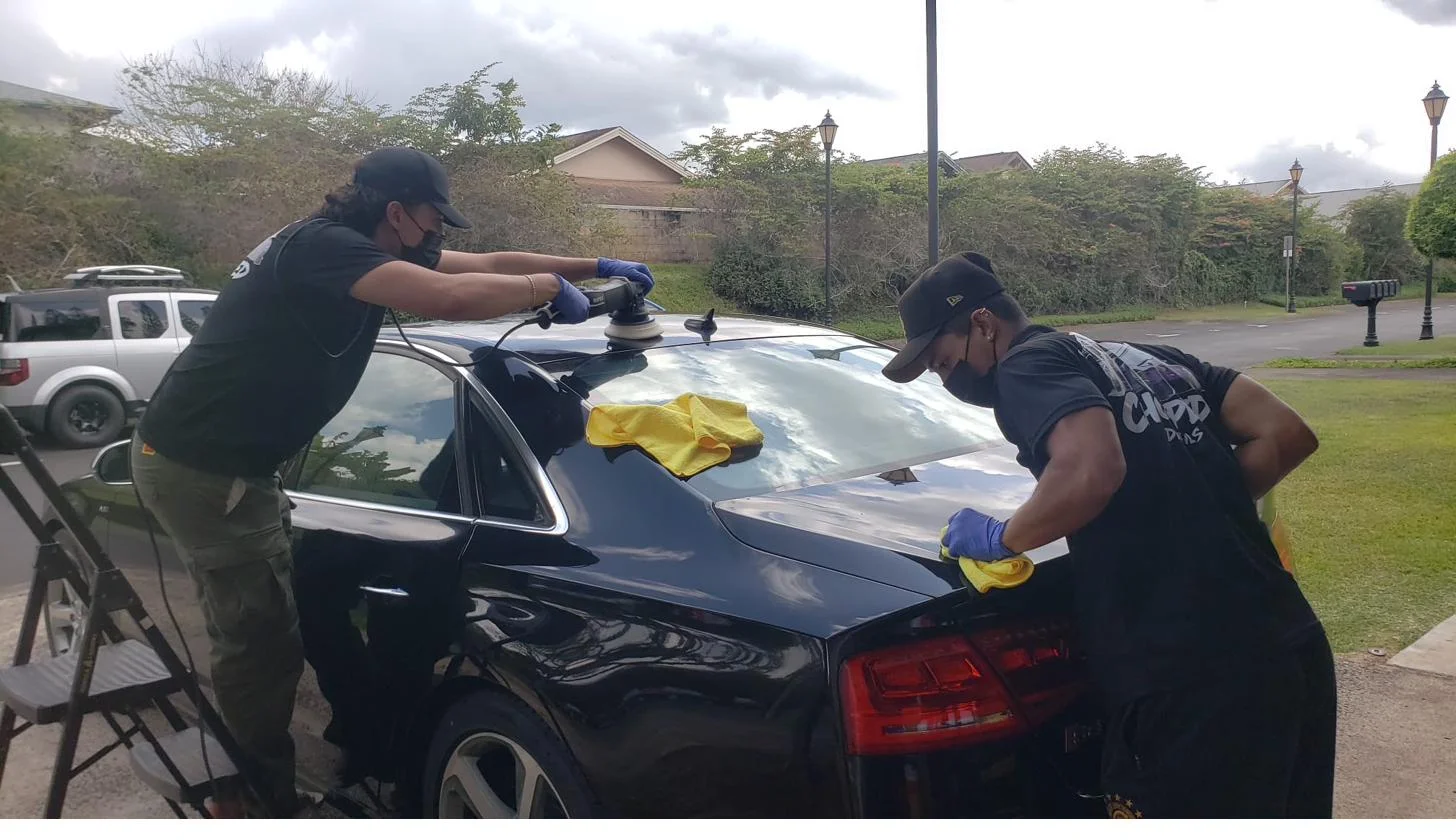 Chopped Details team machine-polishing a black Audi sedan in an Oahu driveway
